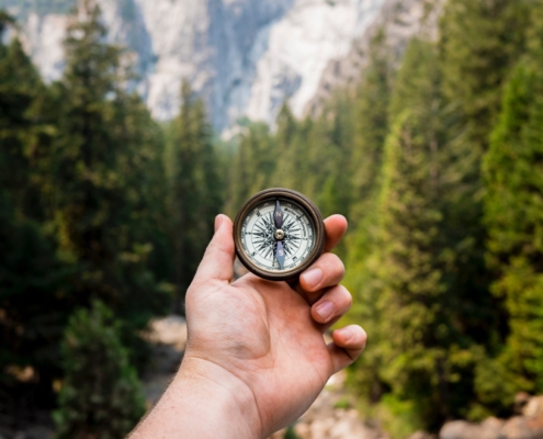 Man holding compass in the woods