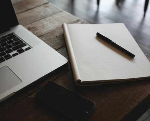 Notepad, laptop, and pen on desk