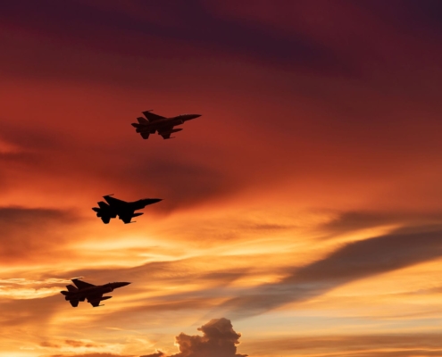 Three fighter jets flying in the dusk sky