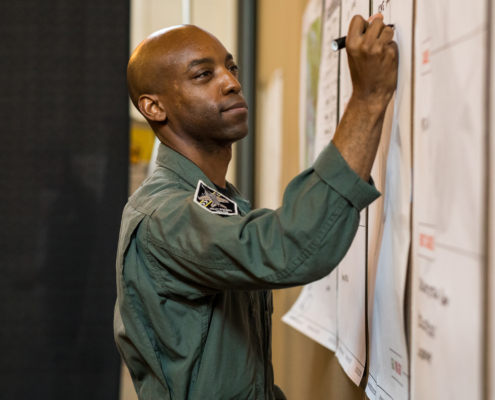 Side View Of Fighter Pilot Writing On Poster On Wall