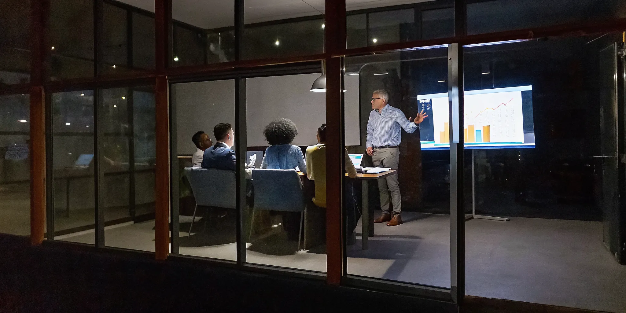 A senior leadership team analyzing executive development ROI dashboards in a modern glass conference room