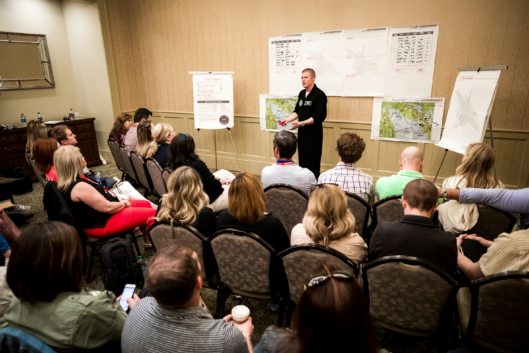 Afterburner facilitator leading a mission briefing with teams seated in groups.
